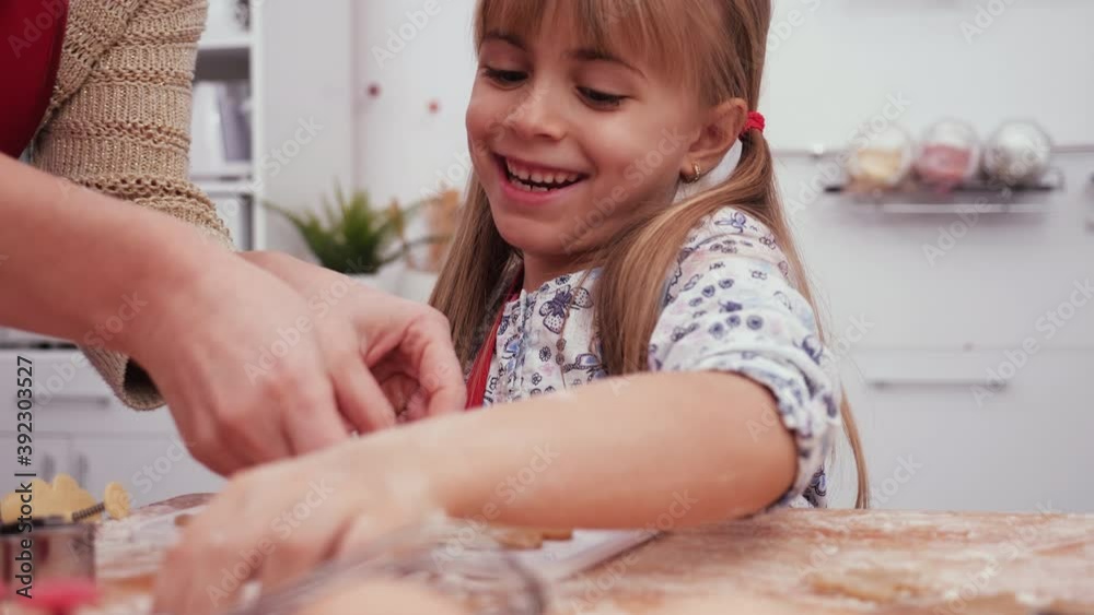 Happy little girl arrange christmas cookies cut from gingerbread dough, on a plate - camera slide