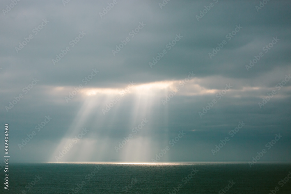 Sunlight streaming through a cloudy sky onto the ocean Sunlight streaming through a cloudy sky onto the ocean