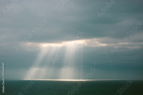 Sunlight streaming through a cloudy sky onto the ocean