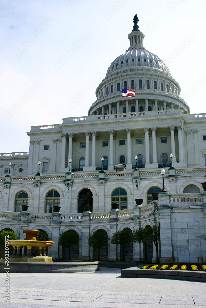 Fototapeta premium American flag in front of Capitol Hill in Washington DC with dome in daylight and facade details