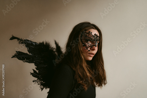 Attractive mysterious woman in black outfit and mask with wings like dark fallen angel photo