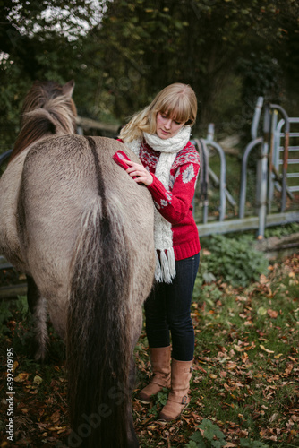 Woman brushing horse crupper on ranch photo