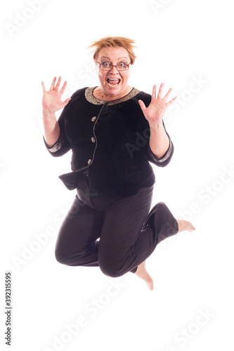 Middle aged woman in black jacket and trousers jumping