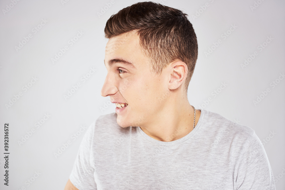 Man in a white t-shirt emotions gestures with hands close-up cropped view light background