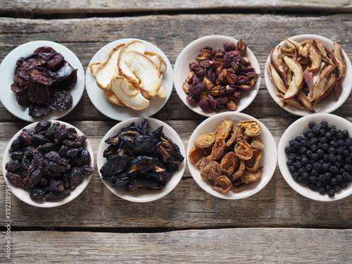 Bowls with various dried fruits on a wooden ancient background. Home preparation of dried fruits.