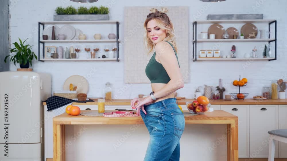 close up portrait Young fitness woman with a slim waist slender figure tries on big pants and shows how to lose weight to the camera in kitchen at home Athletic girl lost weight after diet or exercise close up portrait Young fitness woman with a slim waist slender figure tries on big pants and shows how to lose weight to the camera in kitchen at home Athletic girl lost weight after diet or exercise
