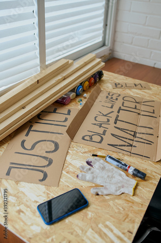 a man draws posters with a black marker that say justice and black lives matter