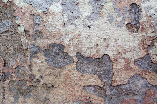 
The wall is covered with many layers of paint and rust, the background looks like unpainted concrete. devastation. photo