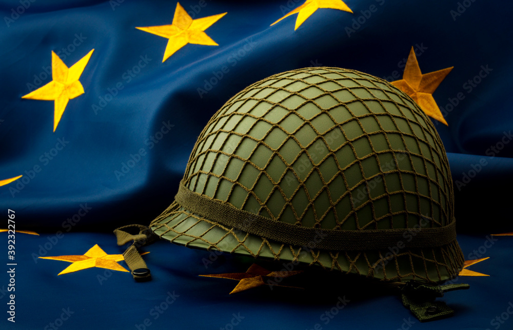 European union army, military uniform and defense of Europe concept with soldier helmet with camouflage pattern and the EU flag in the background