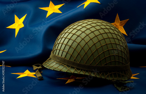 Obraz na płótnie European union army, military uniform and defense of Europe concept with soldier helmet with camouflage pattern and the EU flag in the background w salonie