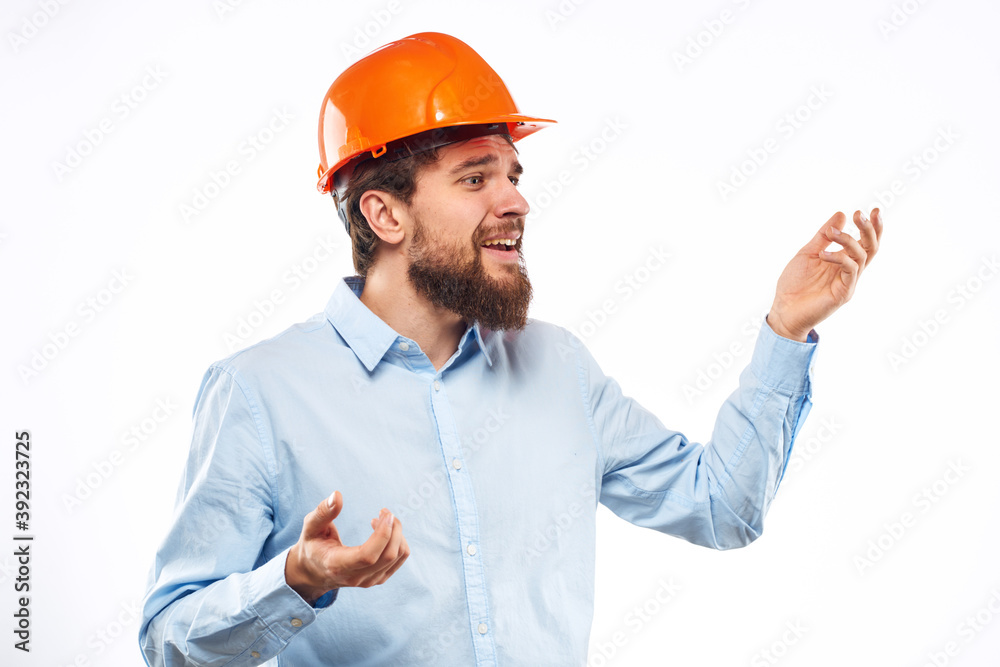 A man in an orange helmet shirt construction industry worked light background A man in an orange helmet shirt construction industry worked light background