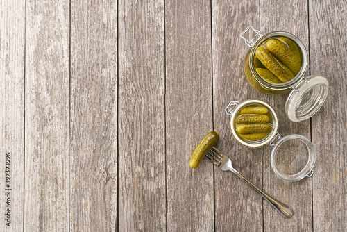 Pickles in jar. Preserved cucumbers in jar on a wooden table, top view.