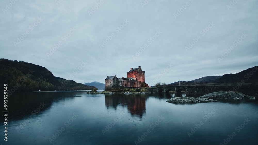 A moody view of Eilean Donan Castle with a reflection in the lake on a foggy day