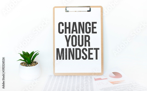 Top view notebook, pen and plant potted on white wood desk background. Lifestyle, business finance, education technology concept. Copy space. Text Change Your Mindset