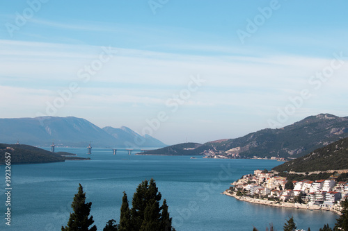 Distant view of a bridge being built in Croatia, connecting the island of Peljesac with the mainland of Croatia, going around the Bosnian Neum territory. Town of Neum visible in the foreground photo