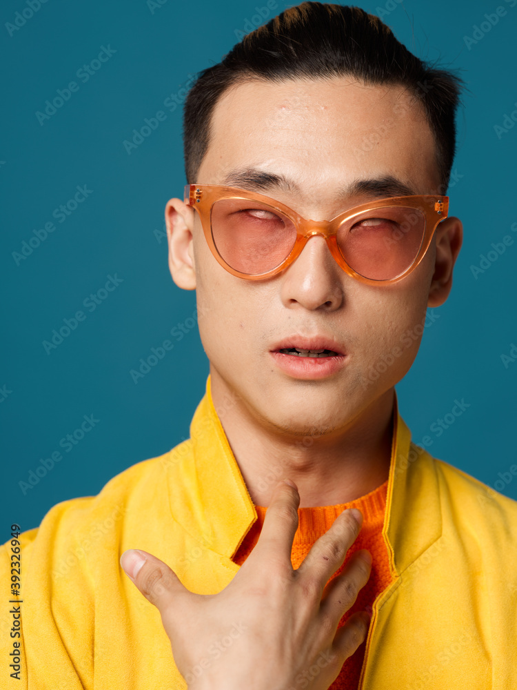 A handsome Asian man with glasses and a yellow jacket gestures with his hands A handsome Asian man with glasses and a yellow jacket gestures with his hands