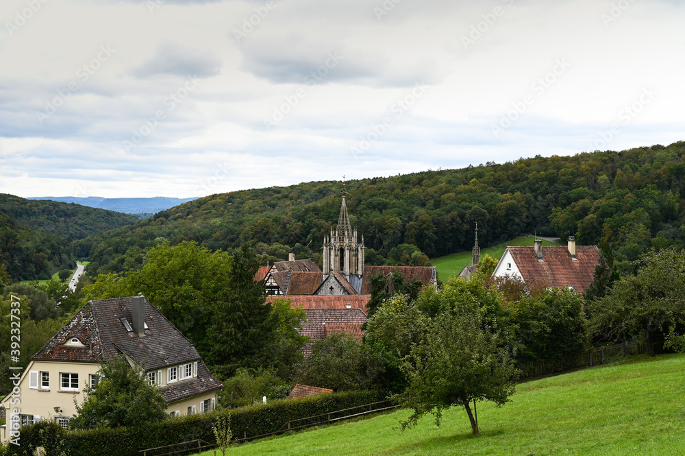 Beautiful view of the village of Bebenhausen with its abbey and historical half-timbered houses. The village is surrounded by colorful forest and fresh green meadows.