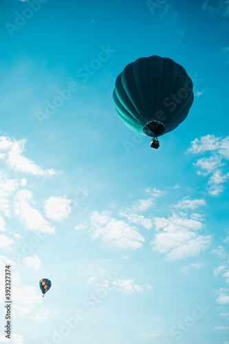 Aquamarine hot air balloons in flight with a cloudy blue sky 