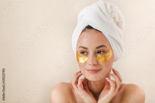 Young beautiful woman with silicone gold eye patches. Facial care at home. Girl with clean skin. Young beautiful girl cares for the skin using patches under the eyes at home.