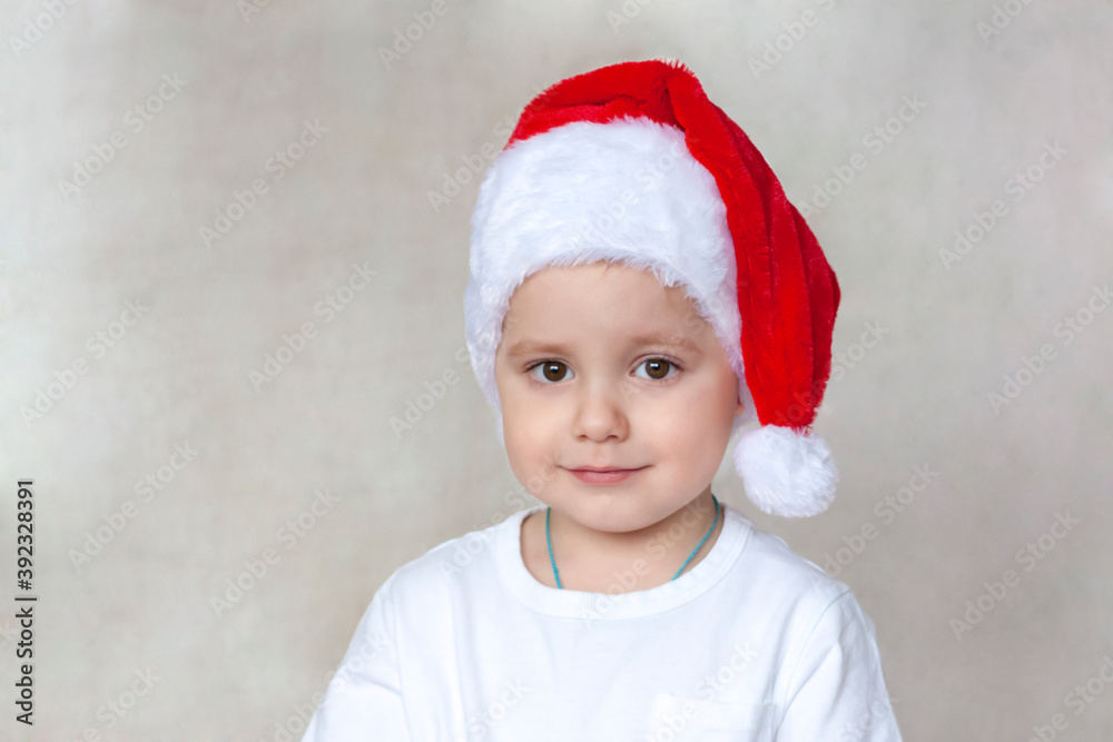 Portrait of a cute little boy in a white t-shirt and Santa Claus hat. Children's emotions. Christmas and new year. Success, bright idea, creative ideas and concepts. Portrait of a cute little boy in a white t-shirt and Santa Claus hat. Children's emotions. Christmas and new year. Success, bright idea, creative ideas and concepts.