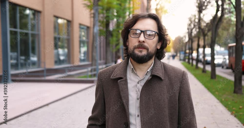 Portrait of happy Caucasian handsome man in good mood standing in front of school outdoors. Male teacher in glasses looking at camera while standing on street. Bearded proffesor. Study concept Portrait of happy Caucasian handsome man in good mood standing in front of school outdoors. Male teacher in glasses looking at camera while standing on street. Bearded proffesor. Study concept
