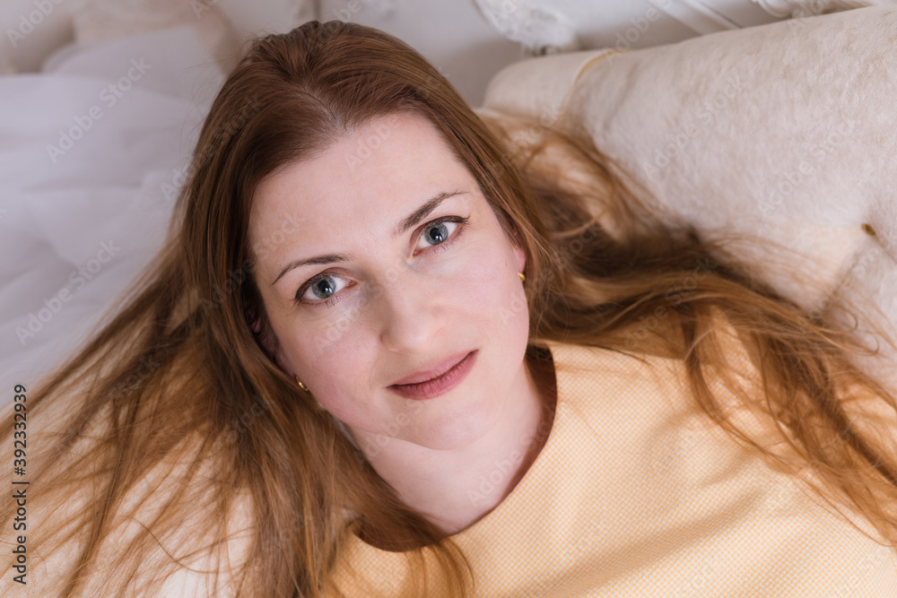 Attractive midle aged woman laying on sofa and looking up into the camera Attractive midle aged woman laying on sofa and looking up into the camera