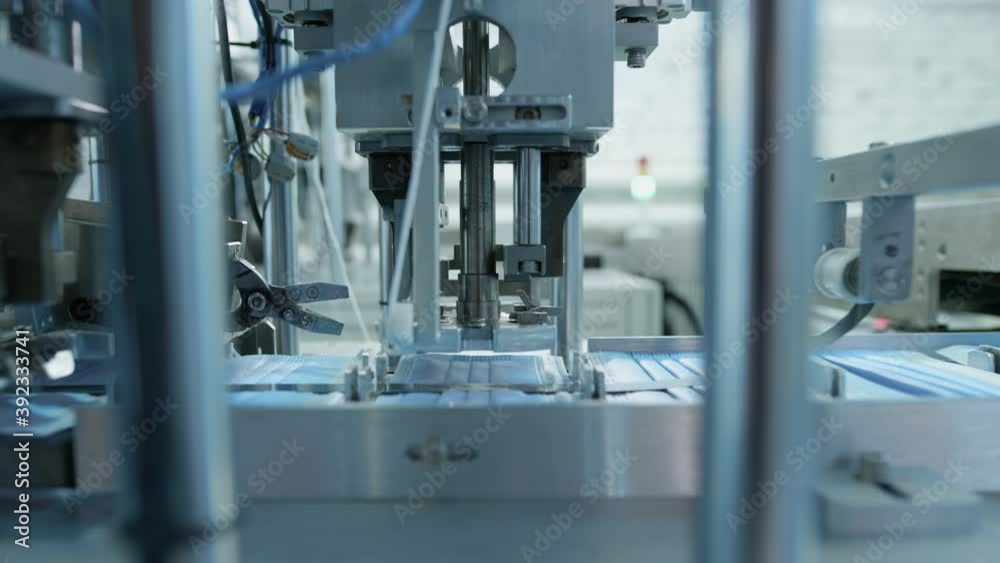 Production of medical three-layer blue or white masks. New masks move on a conveyor belt. Face masks for the work of doctors with patients. Making protective masks during the coronavirus pandemic Production of medical three-layer blue or white masks. New masks move on a conveyor belt. Face masks for the work of doctors with patients. Making protective masks during the coronavirus pandemic