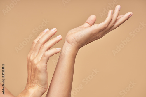 Spa treatment. Beautiful female hands isolated on beige background