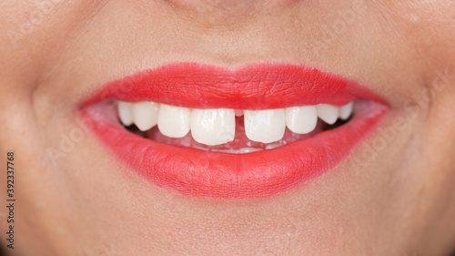 Woman with tooth gap and red lips smiles
