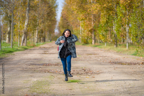 outdoors lifestyle portrait of young happy and pretty Asian Japanese woman jumping carefree and cheerful at beautiful city park in vibrant yellow and orange Autumn tree leaves © TheVisualsYouNeed