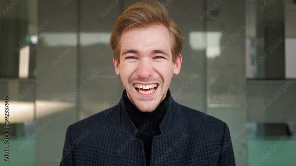 Portrait. Happy european man laughs funny in urban background. Emotional attractive guy looking at camera smiling. Slow motion Portrait. Happy european man laughs funny in urban background. Emotional attractive guy looking at camera smiling. Slow motion