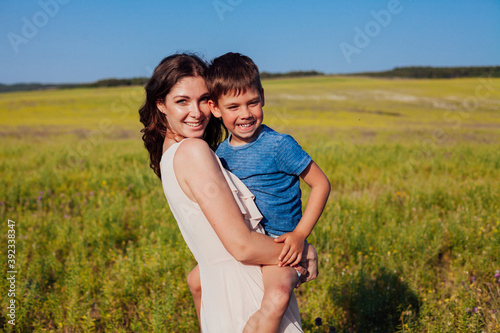 Woman holds baby in her arms in nature in a field with flowers