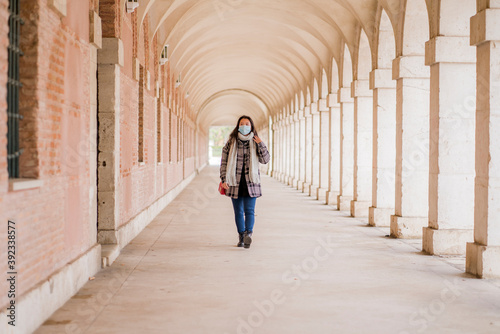 new normal tourism and holidays travel - young and beautiful Asian Chinese woman in face mask enjoying city tour walking around historic district on sunny winter day during covid19