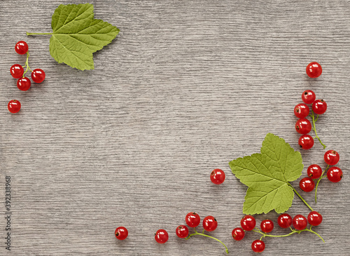 Red currant berries with leaves frame on a wooden surface