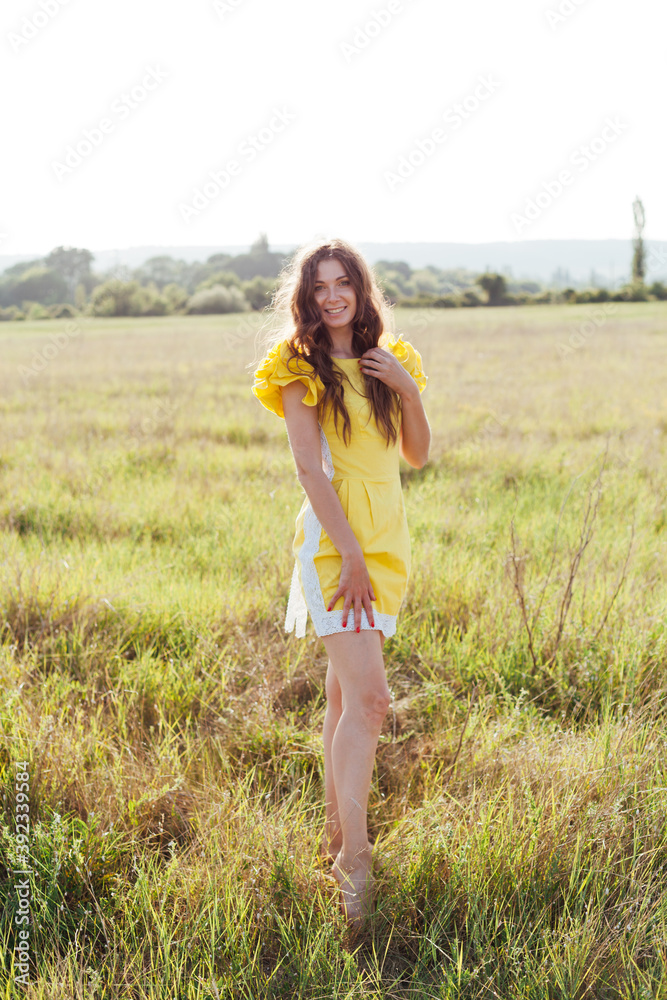 Beautiful woman in yellow dress walks on the field with flowers Beautiful woman in yellow dress walks on the field with flowers