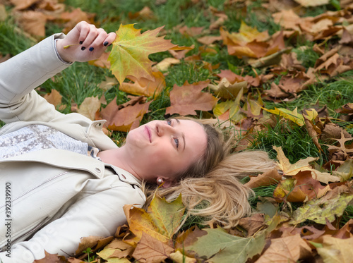 Young Woman Laying in the Grass in Autumn Park