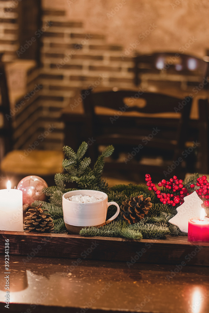 Christmas hot chocolate with mini marshmellows in an old ceramic mug with candles on a wooden background Christmas hot chocolate with mini marshmellows in an old ceramic mug with candles on a wooden background
