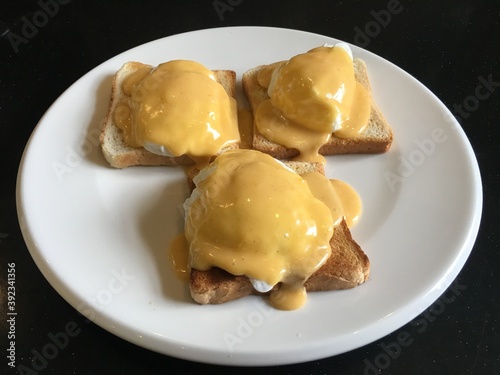 Eggs Benedict with Hollandaise sauce on a white plate