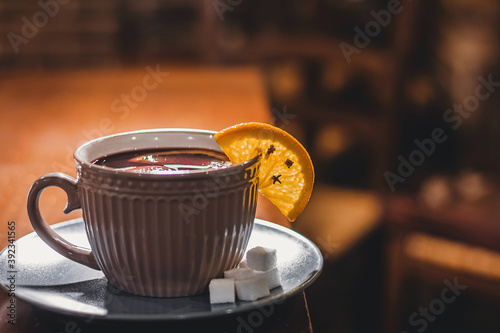 Red hot drink glintwein with spices, cinnamon, anise, fruits, brown sugar on an old wooden table. New Year and Christmas holidays concept. Mulled wine and glintwein photo