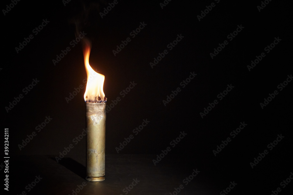 War candle. The candle burns in an empty sleeve. As a symbol of war and victims. Candle for remembering day. Located on black background. A candle used by the soldiers of the Second World War War candle. The candle burns in an empty sleeve. As a symbol of war and victims. Candle for remembering day. Located on black background. A candle used by the soldiers of the Second World War