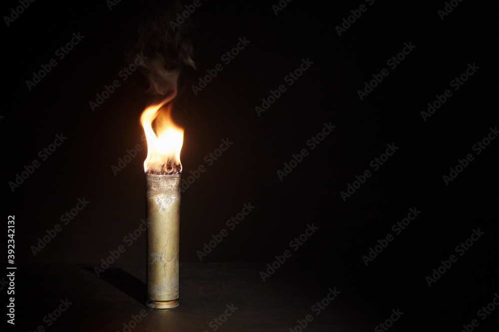 War candle. The candle burns in an empty sleeve. As a symbol of war and victims. Candle for remembering day. Located on black background. A candle used by the soldiers of the Second World War War candle. The candle burns in an empty sleeve. As a symbol of war and victims. Candle for remembering day. Located on black background. A candle used by the soldiers of the Second World War