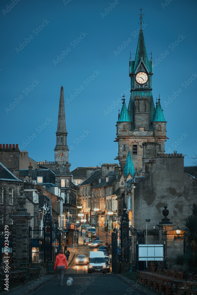 DUNFERMLINE, UNITED KINGDOM - NOVEMBER 04, 2020: A city street of old historic town in the evening with walking people and street lights. Bridge Street, Dunfermline, Scotland DUNFERMLINE, UNITED KINGDOM - NOVEMBER 04, 2020: A city street of old historic town in the evening with walking people and street lights. Bridge Street, Dunfermline, Scotland