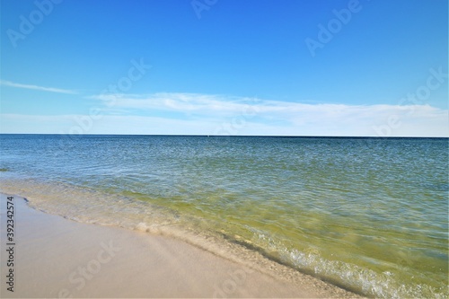 The seascape  a beautiful blank view from the coast of the Gulf of Mexico  calm ocean waters without waves over the horizon converge with a clear blue sky  in the foreground you can see the coast with