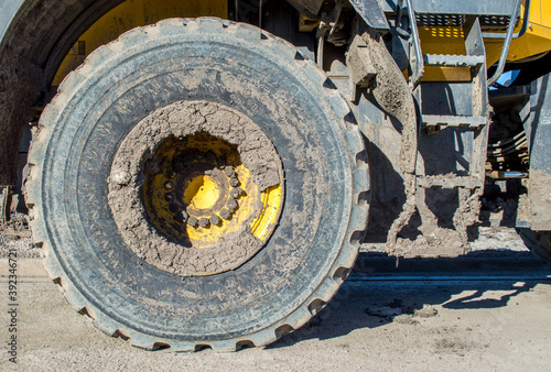 heavy duty bulldozer tire and steps caked in mud on a sunny day