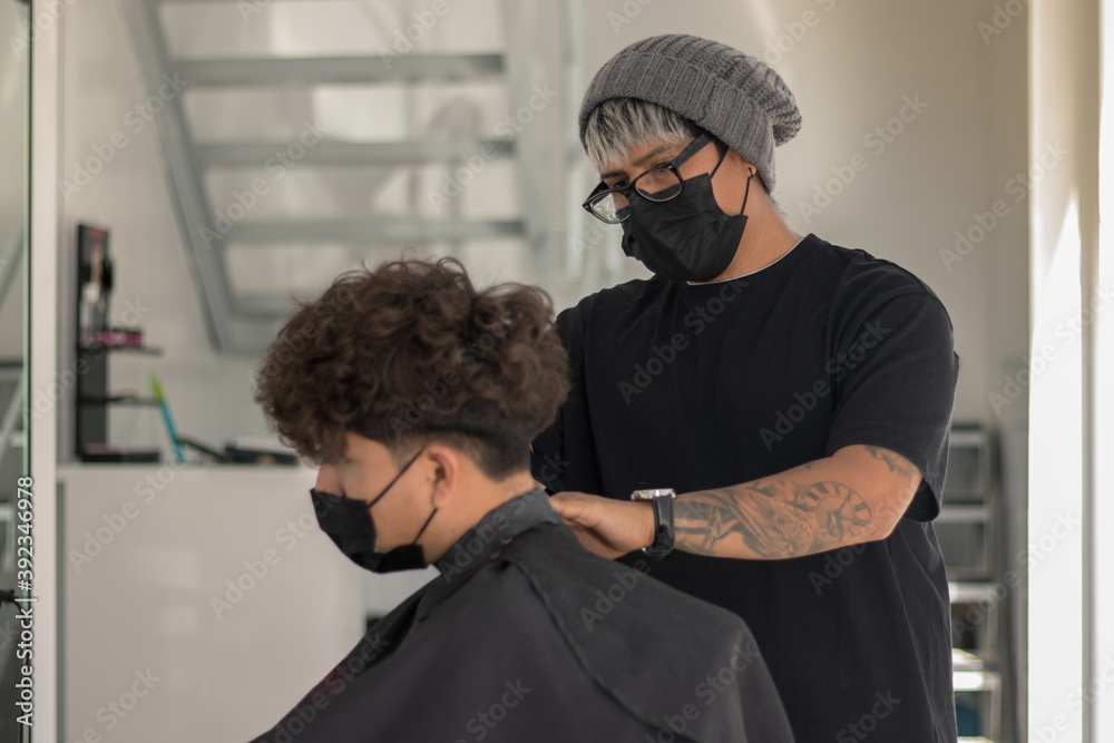 Session in a hair salon with a young hairdresser with a mask cutting the hair of a boy with a mask in times of pandemic