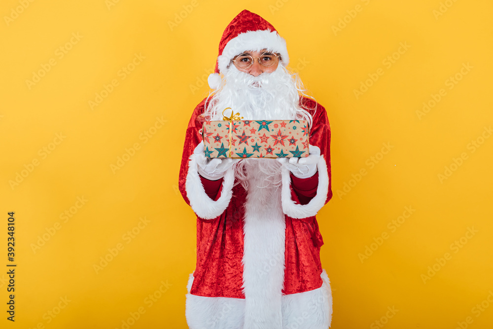 Santa Claus hold a gift on yellow background. Christmas concept