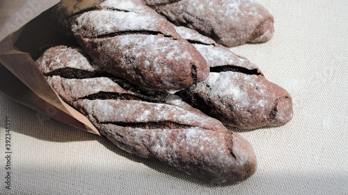 Homemade rye French baguettes in a craft package. Against the background of gray linen fabric