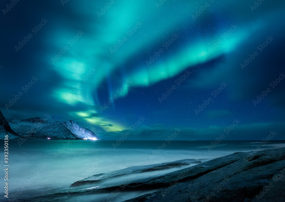 Aurora borealis in Norway. Green northern lights above mountains and ocean. Night winter landscape with aurora. Natural p henomenon background in Norway.