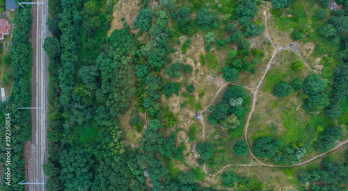 Top down aerial look to paths in park on hill and train rails on side
