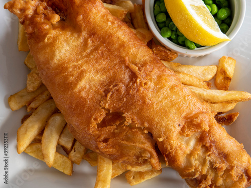 Konstfotografi closeup of traditional British pub fare, a crispy battered haddock filet with fr